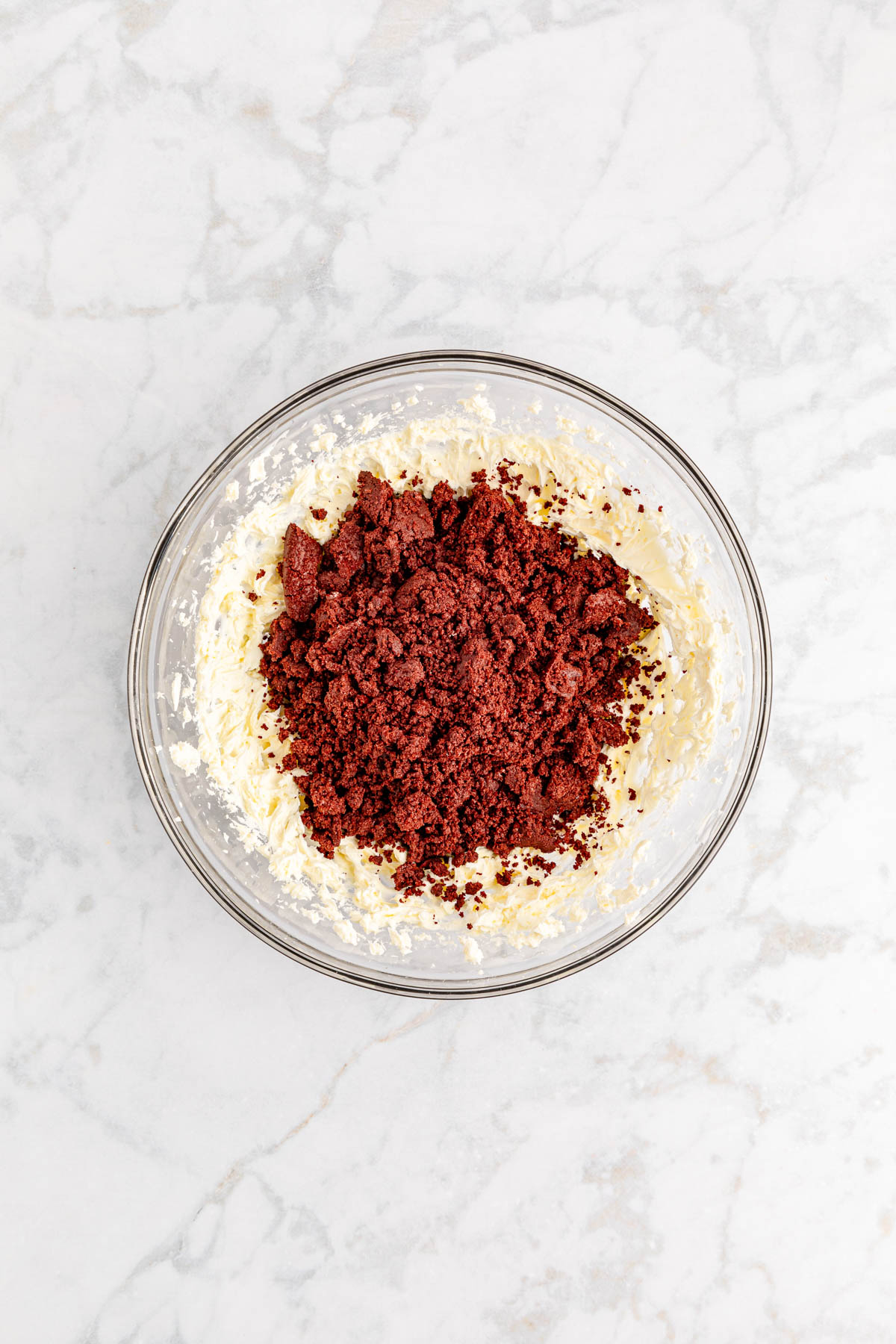 Red velvet Oreo crumbs and cream cheese in a glass bowl.