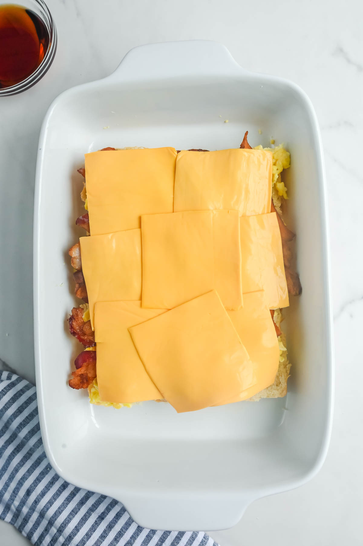Breakfast casserole with bacon and cheese in a white dish.