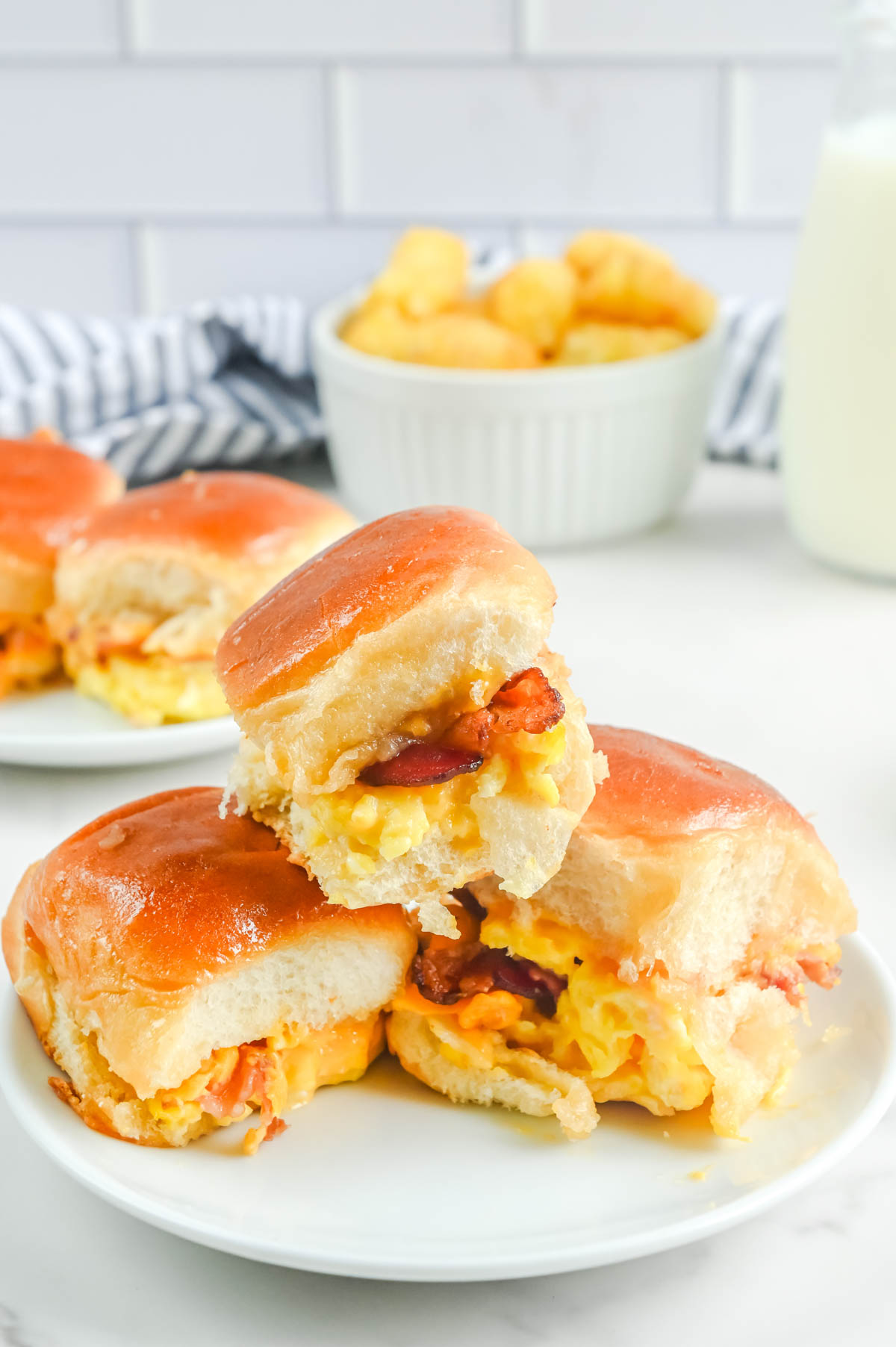 Breakfast sliders with bacon and eggs on a plate.