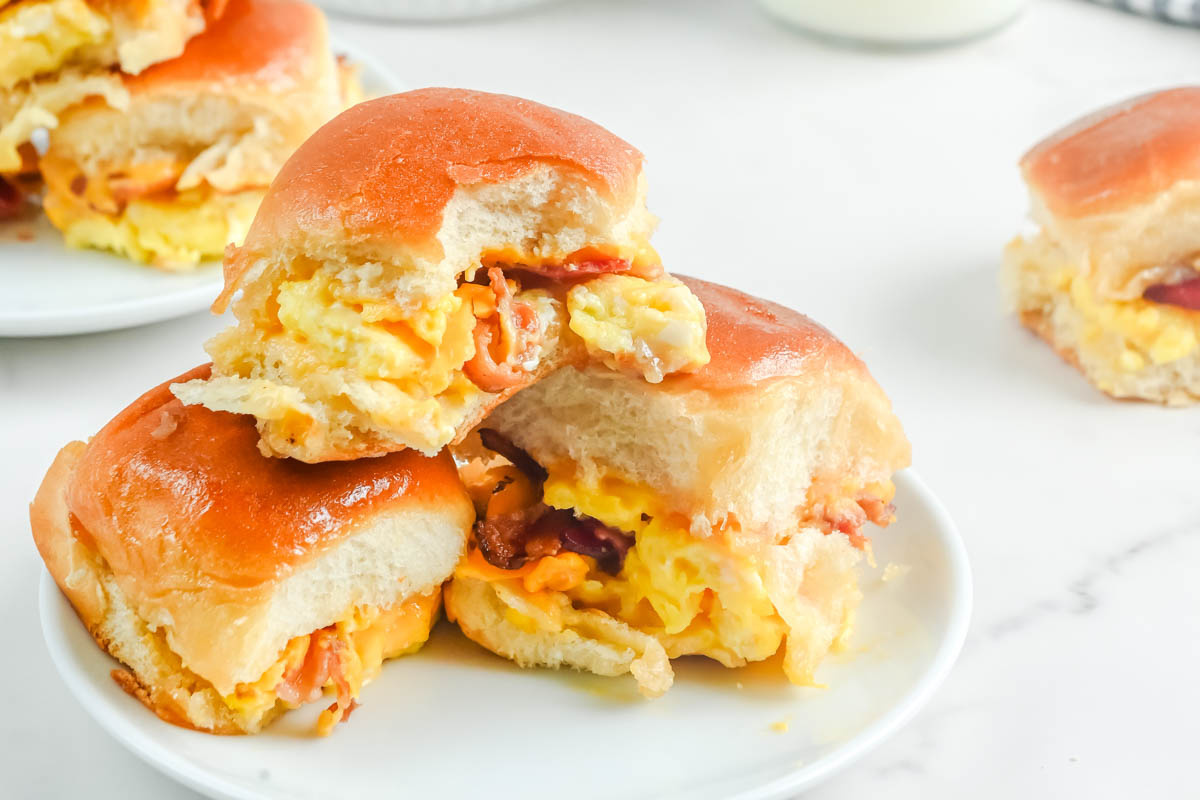 Egg and bacon sliders on a white plate.