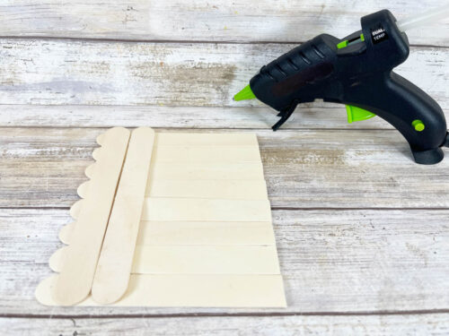 A glue gun and a piece of paper on a wooden table.
