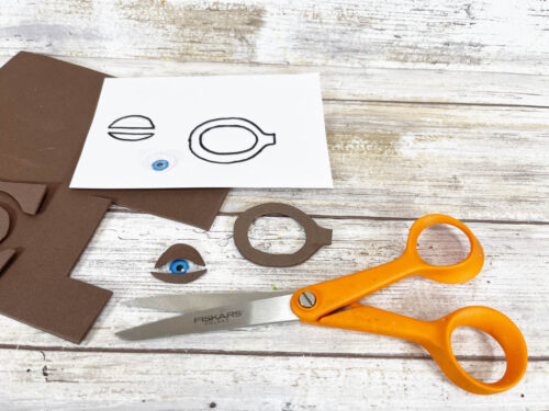 A pair of scissors and a piece of brown paper.