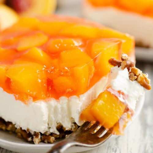 Peach cheesecake on a plate with a fork.