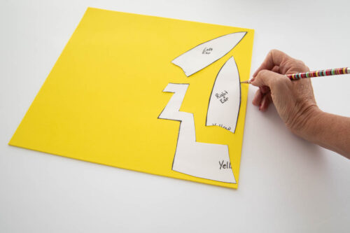 A person tracing shapes onto yellow craft foam
