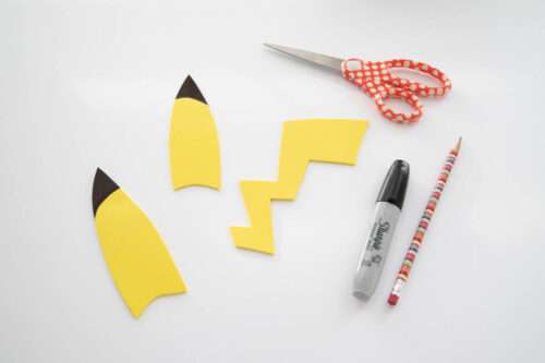 Pokemon pikachu cut outs and scissors on a white table.