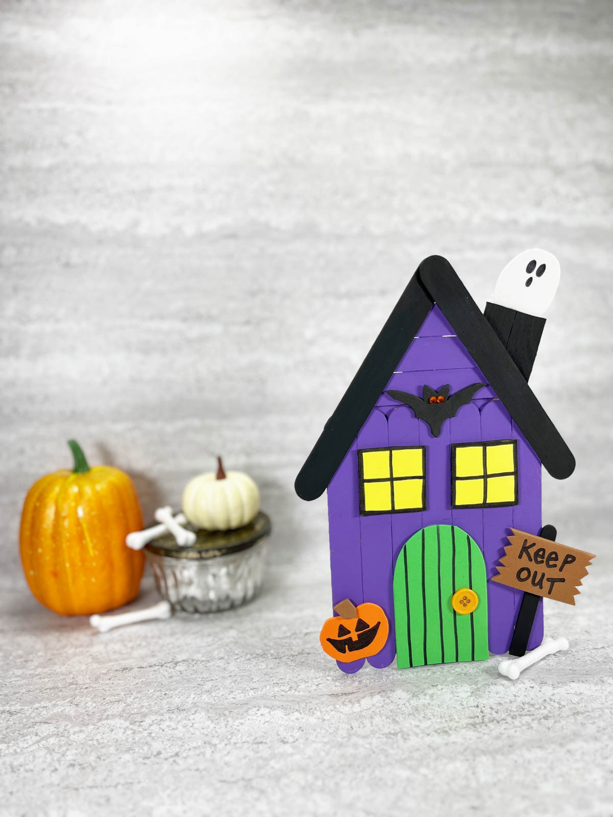 A purple house with a ghost and pumpkins.