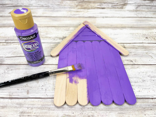 Wooden craft sticks painted purple with bottle of paint and paintbrush