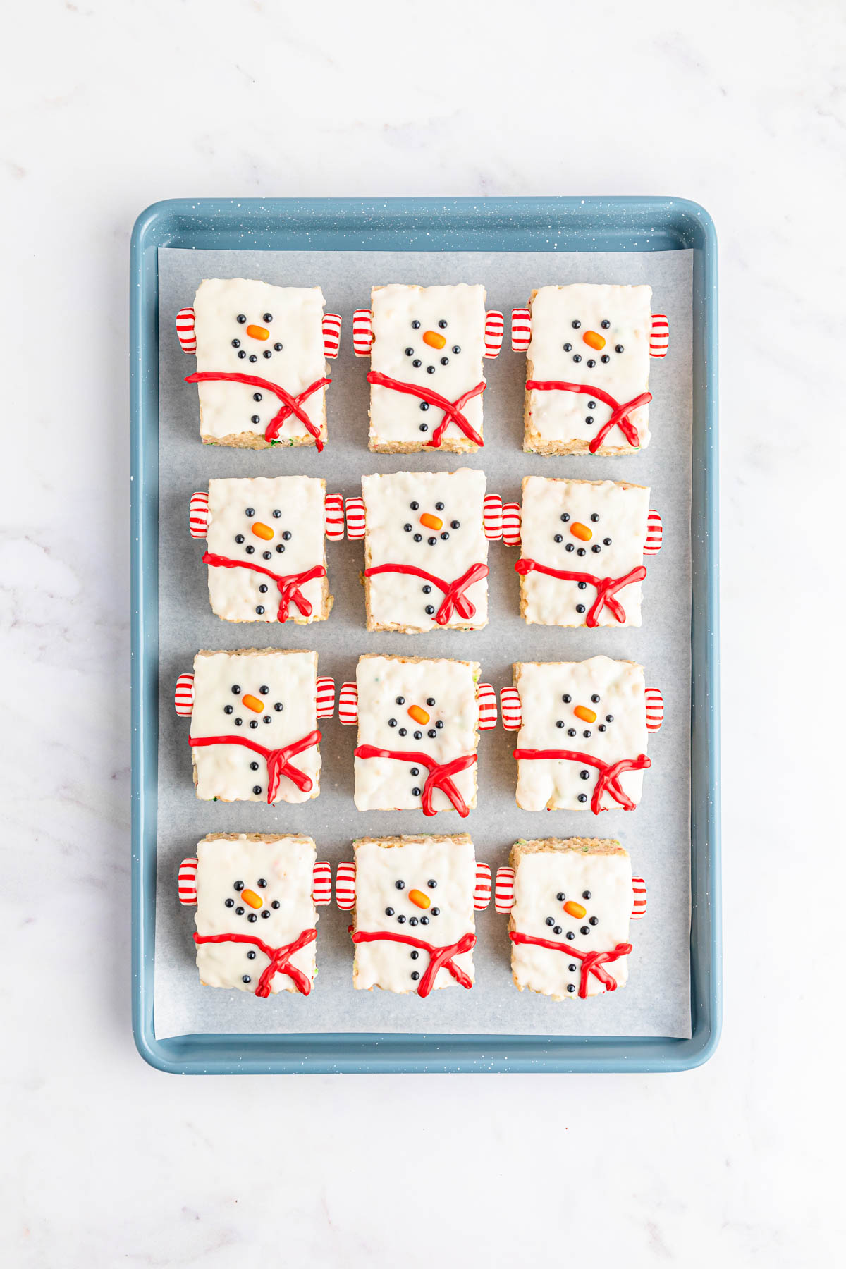 Snowman Rice Krispie treats with red candy scarves on a tray.