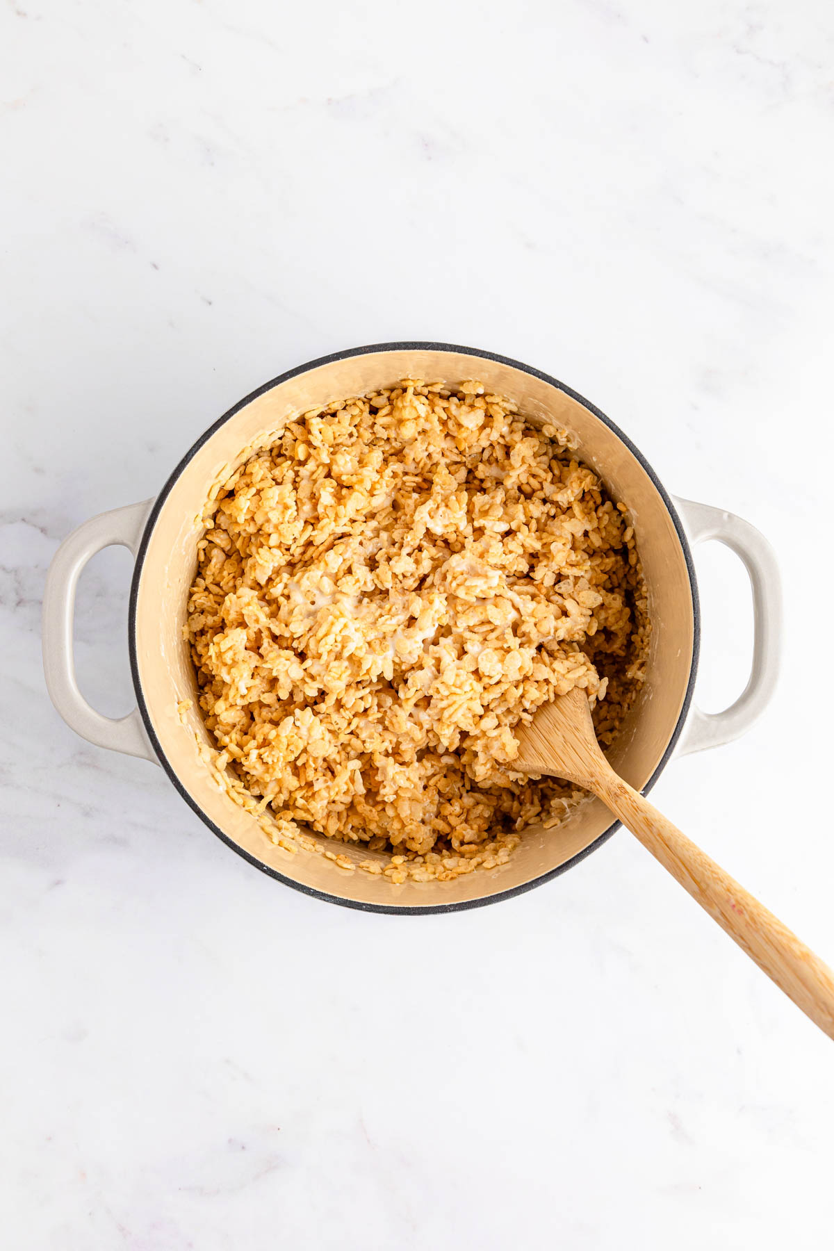 Rice Krispie treat mixture in a pot with a wooden spoon.
