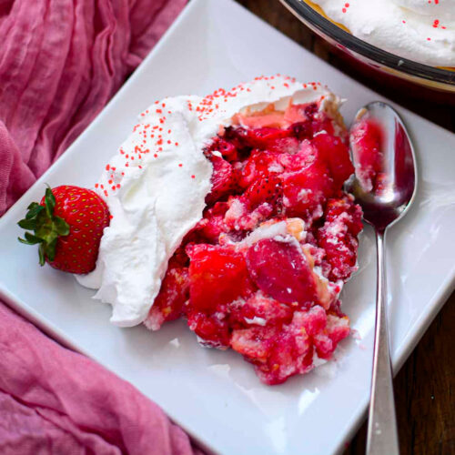 Strawberry pie with whipped cream on a white plate.