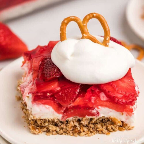 Strawberry pretzel salad on a plate with whipped cream and pretzels.
