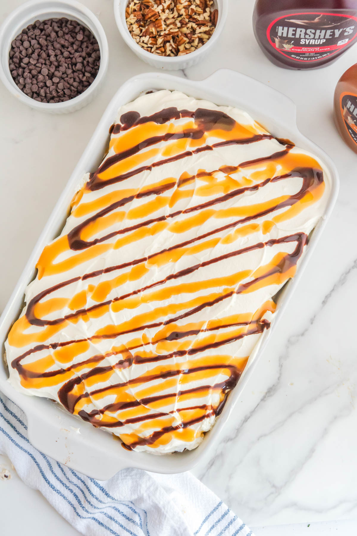 A baking dish with chocolate and caramel sauce drizzled over ice cream sandwich cake