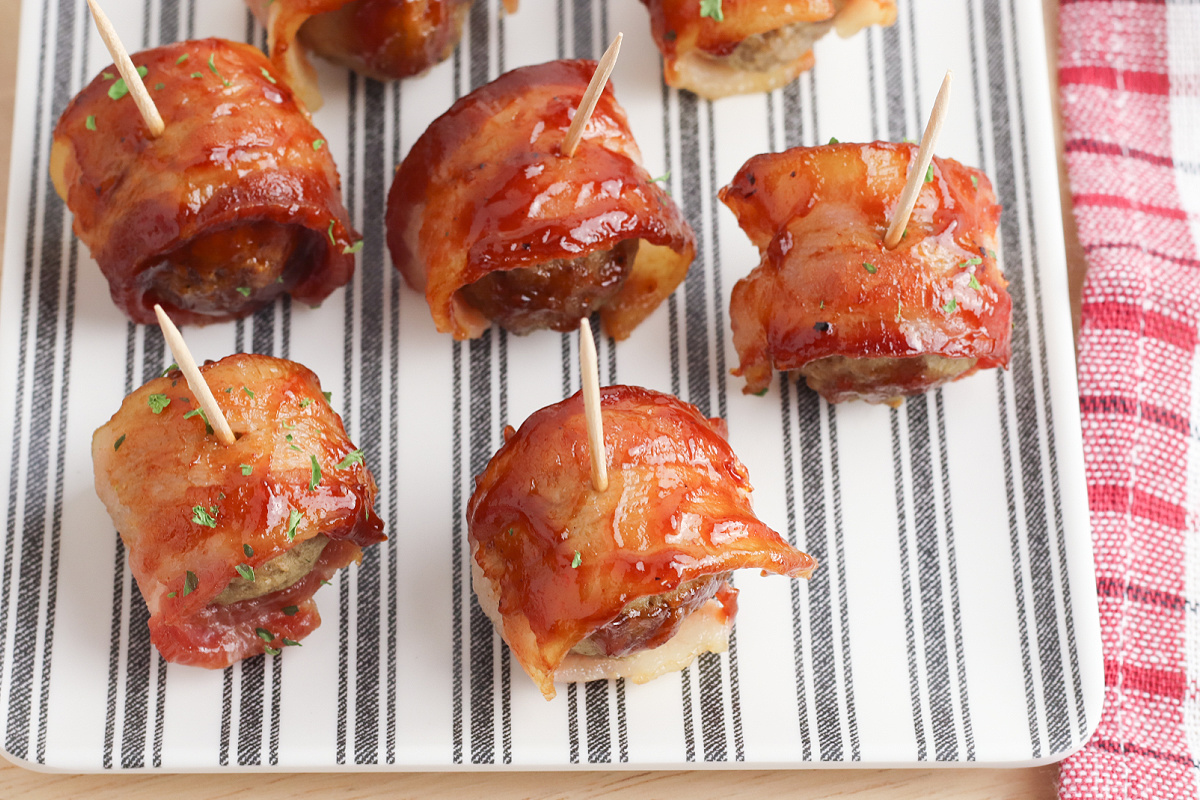 Bacon wrapped meatballs on a plate with toothpicks.