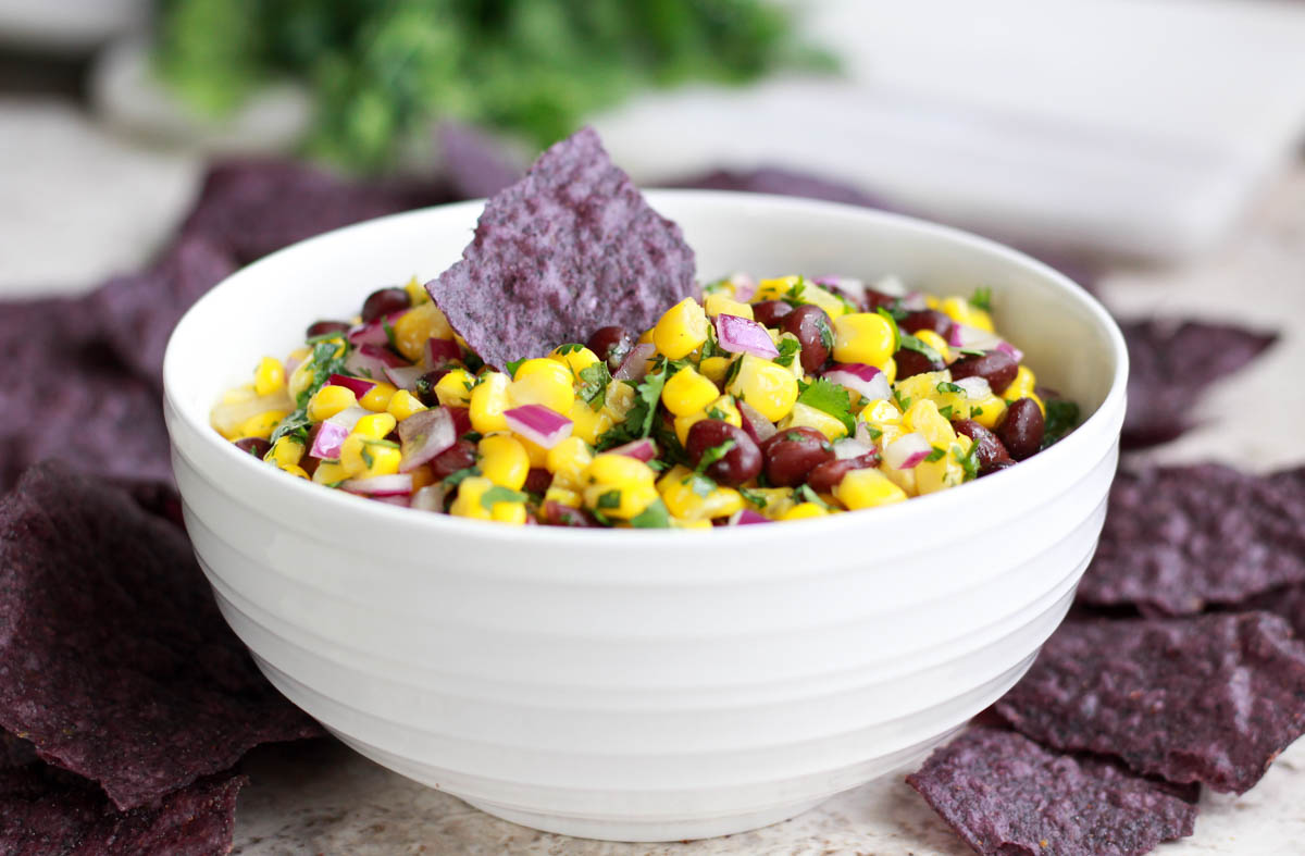 A bowl of black bean salsa with tortilla chips.