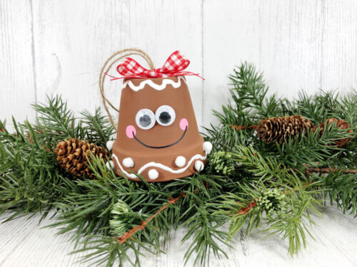 A gingerbread ornament with a red bow and pine cones.