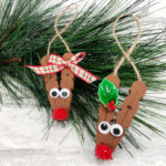 Two reindeer ornaments hanging on a Christmas branch