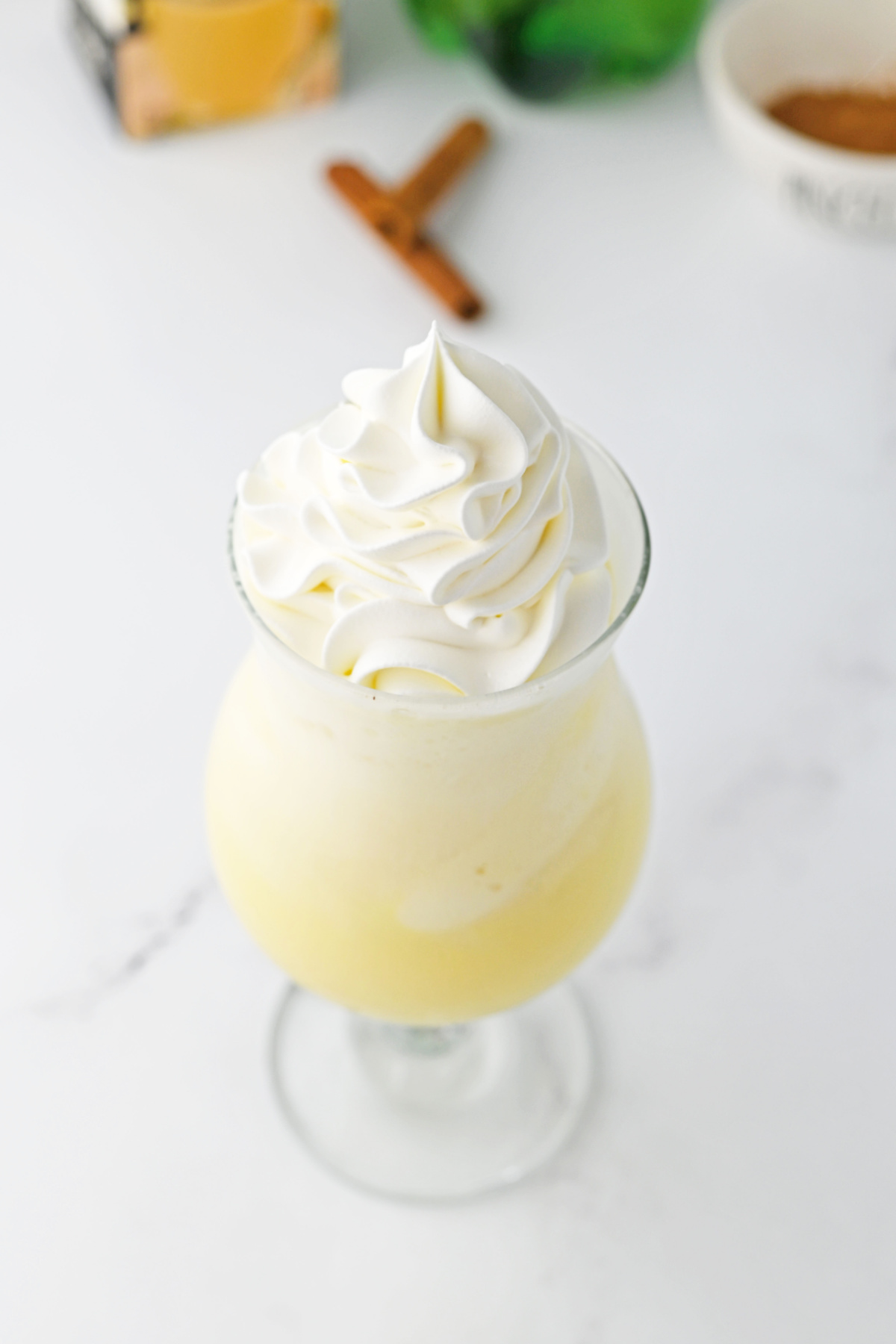 An eggnog float with whipped cream and a cinnamon stick.