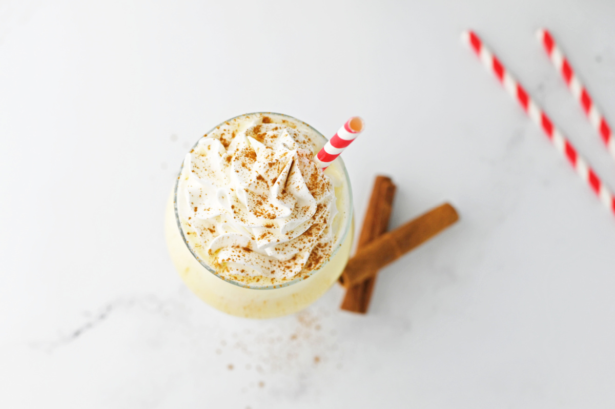 A drink with whipped cream and cinnamon sticks.