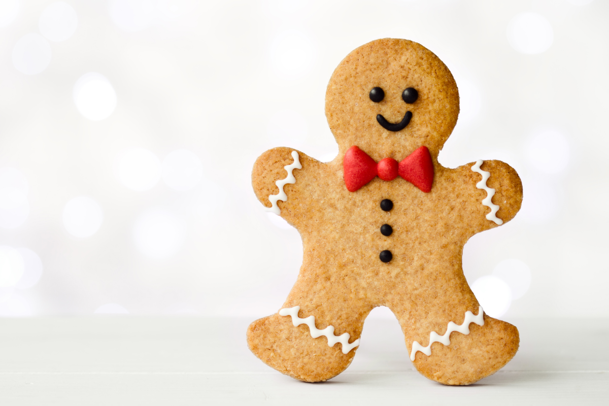A gingerbread man with a red bow tie on a white background.