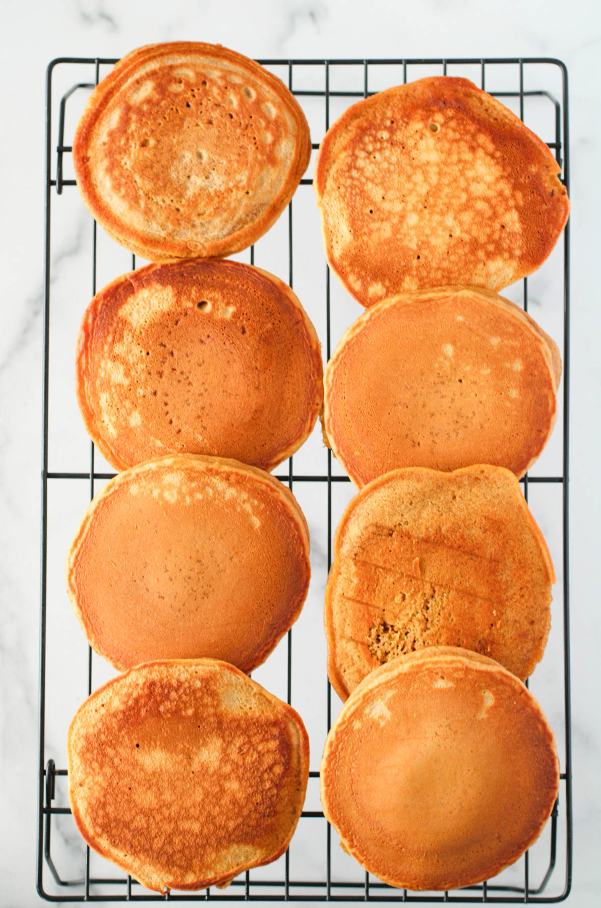 A stack of pancakes on a cooling rack.