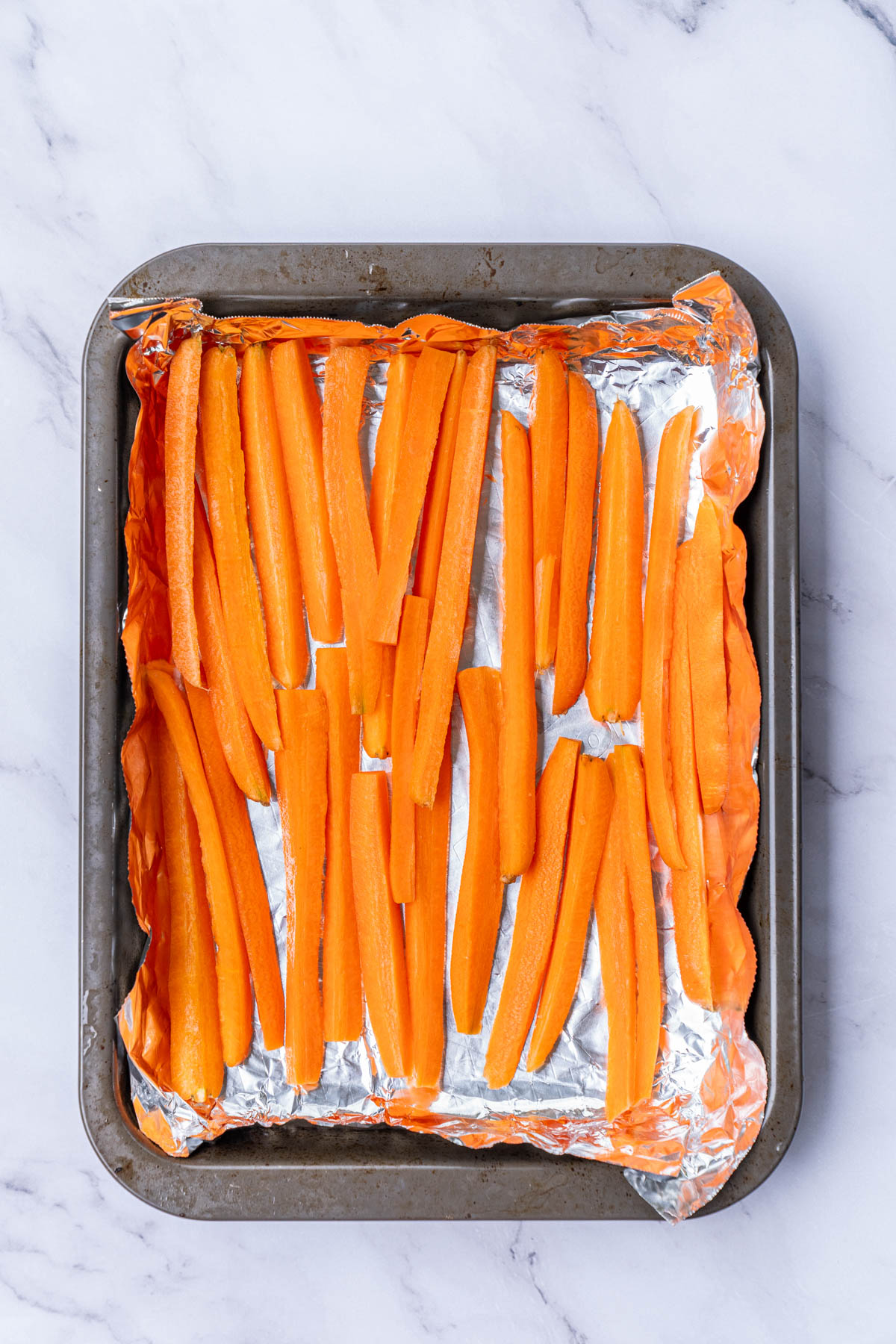 Carrots in foil on a baking sheet.