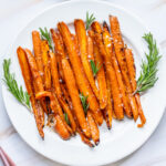 Roasted carrots on a plate with rosemary sprigs.