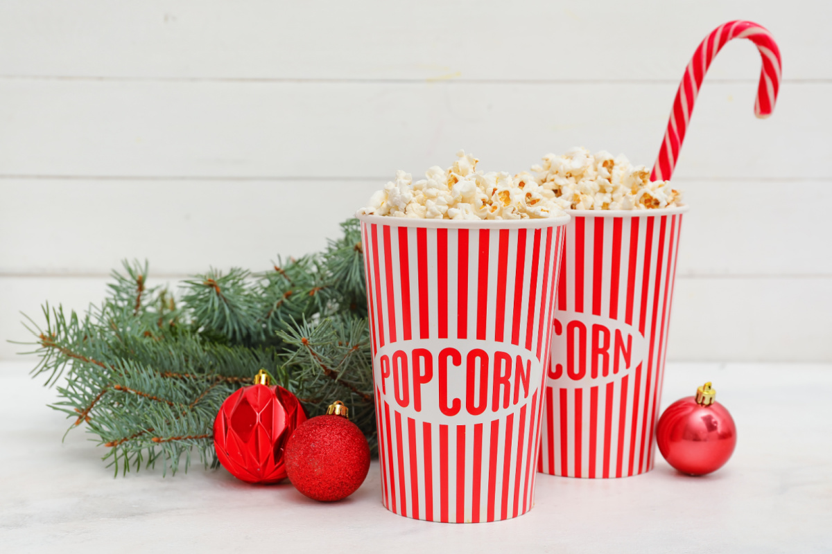 Two red and white popcorn cups with candy canes and christmas decorations.