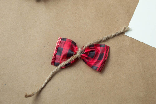 A red and black plaid bow on a piece of brown paper.