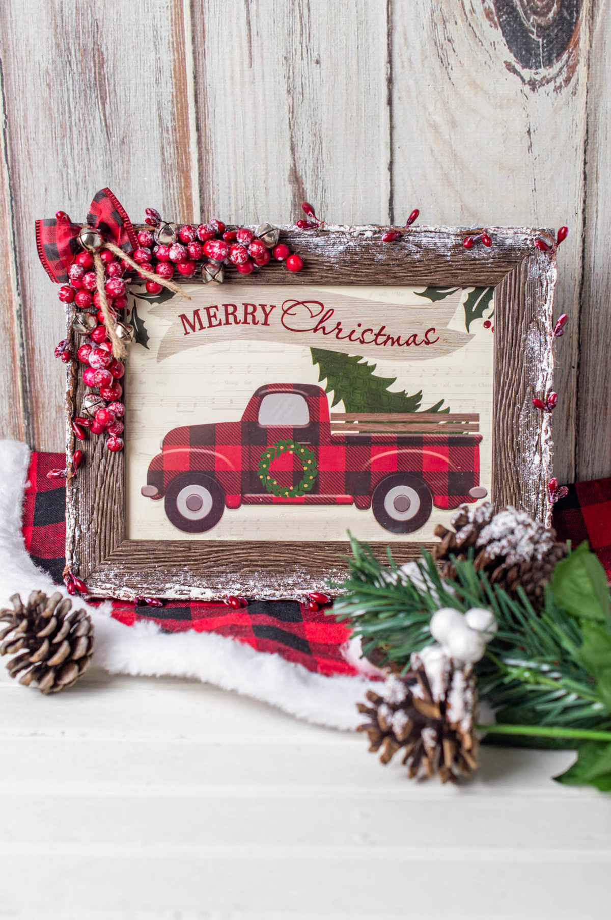 A merry christmas truck framed with holly and pine cones.