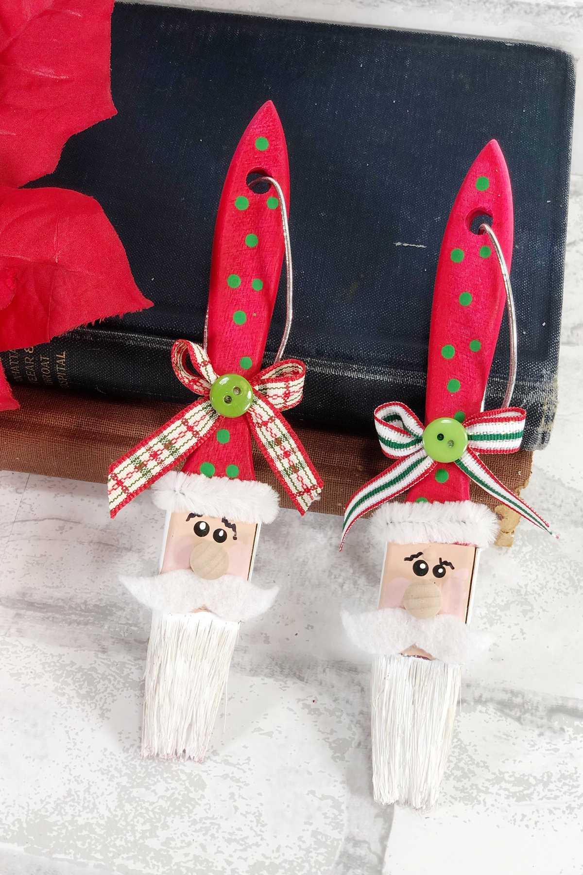 Paintbrushes made into Santa ornaments leaning against book