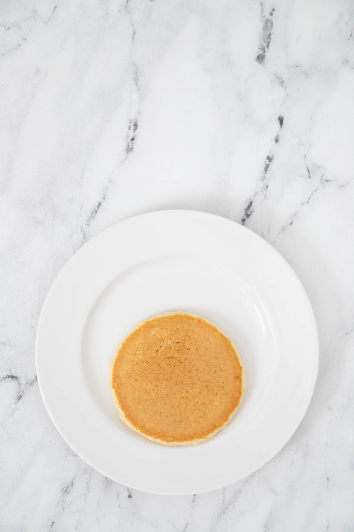 A white plate with a pancake on it.