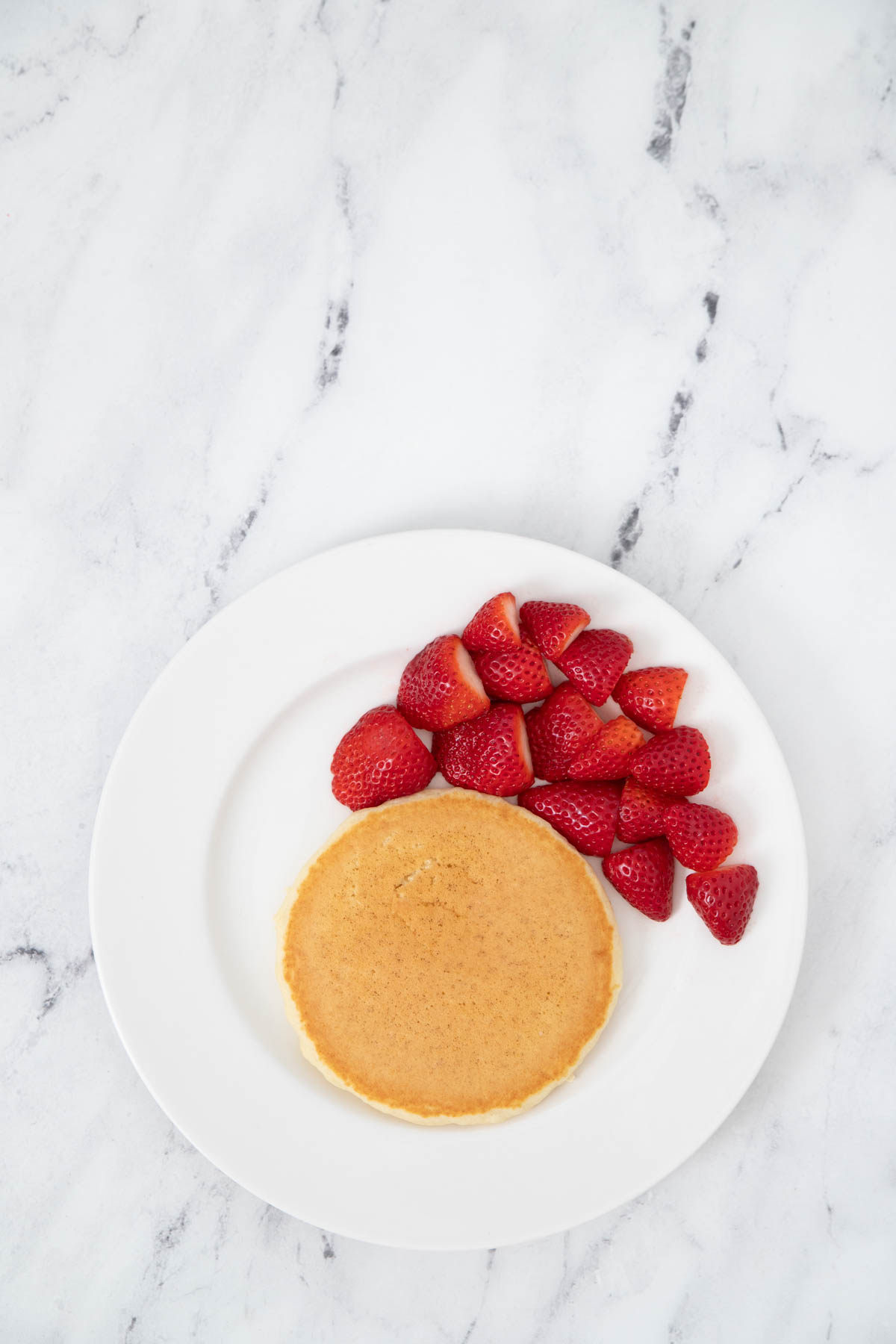 Pancakes with strawberries on a white plate.
