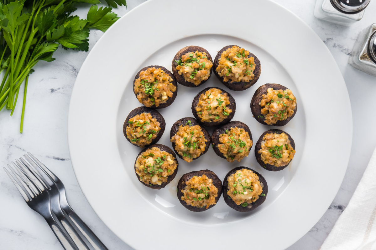 Stuffed mushrooms on a white plate with parsley.