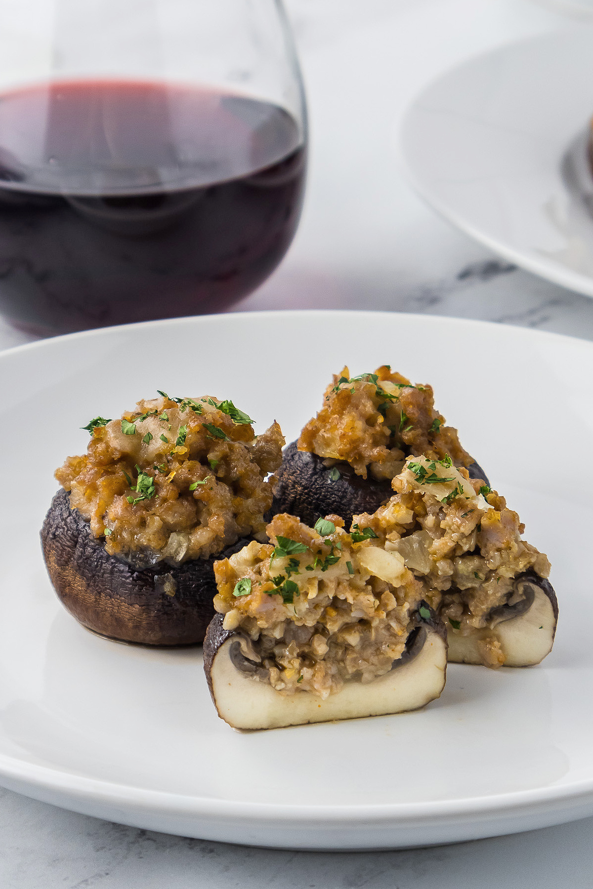 Stuffed mushrooms on a plate next to a glass of wine.