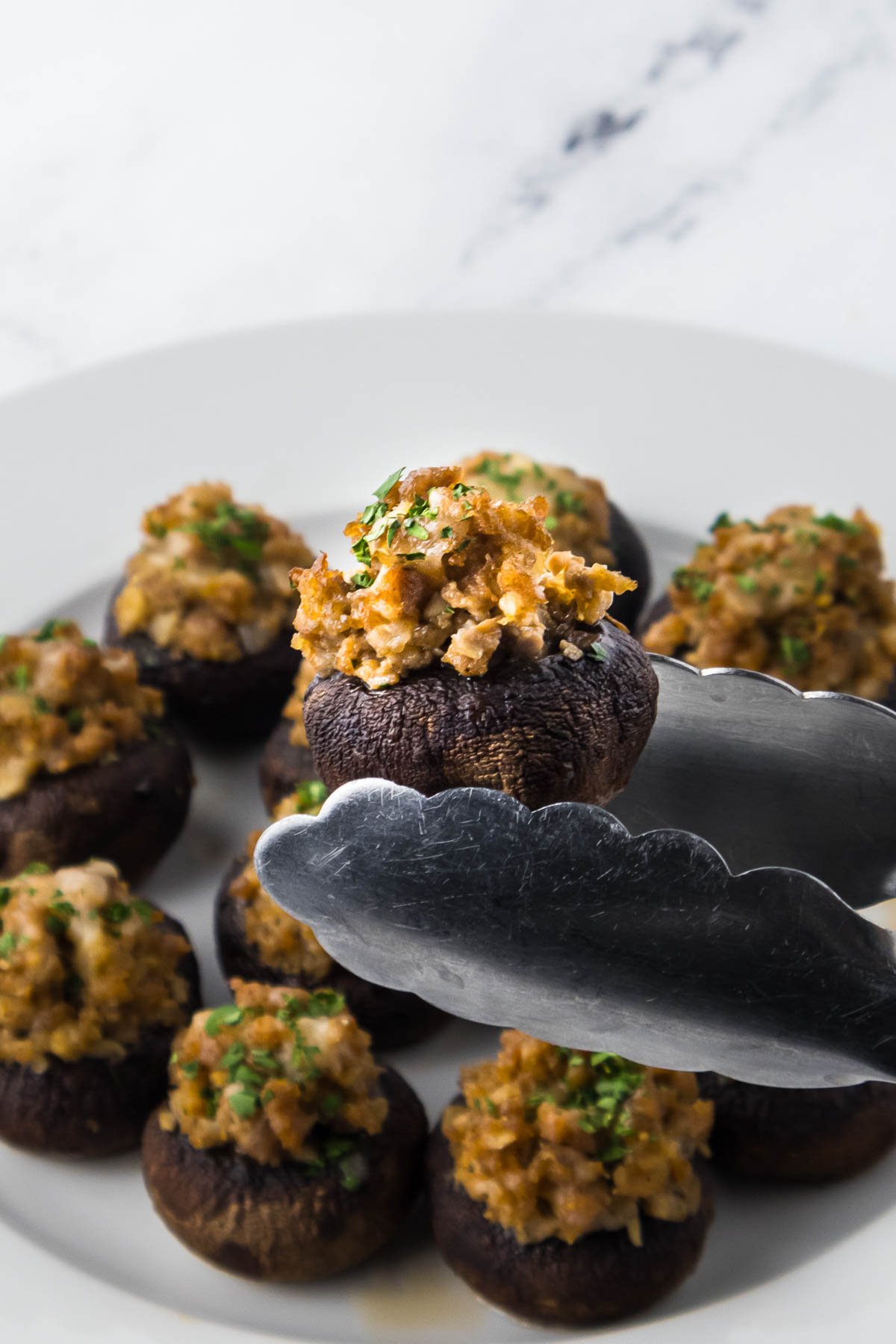Stuffed mushrooms on a plate with tongs
