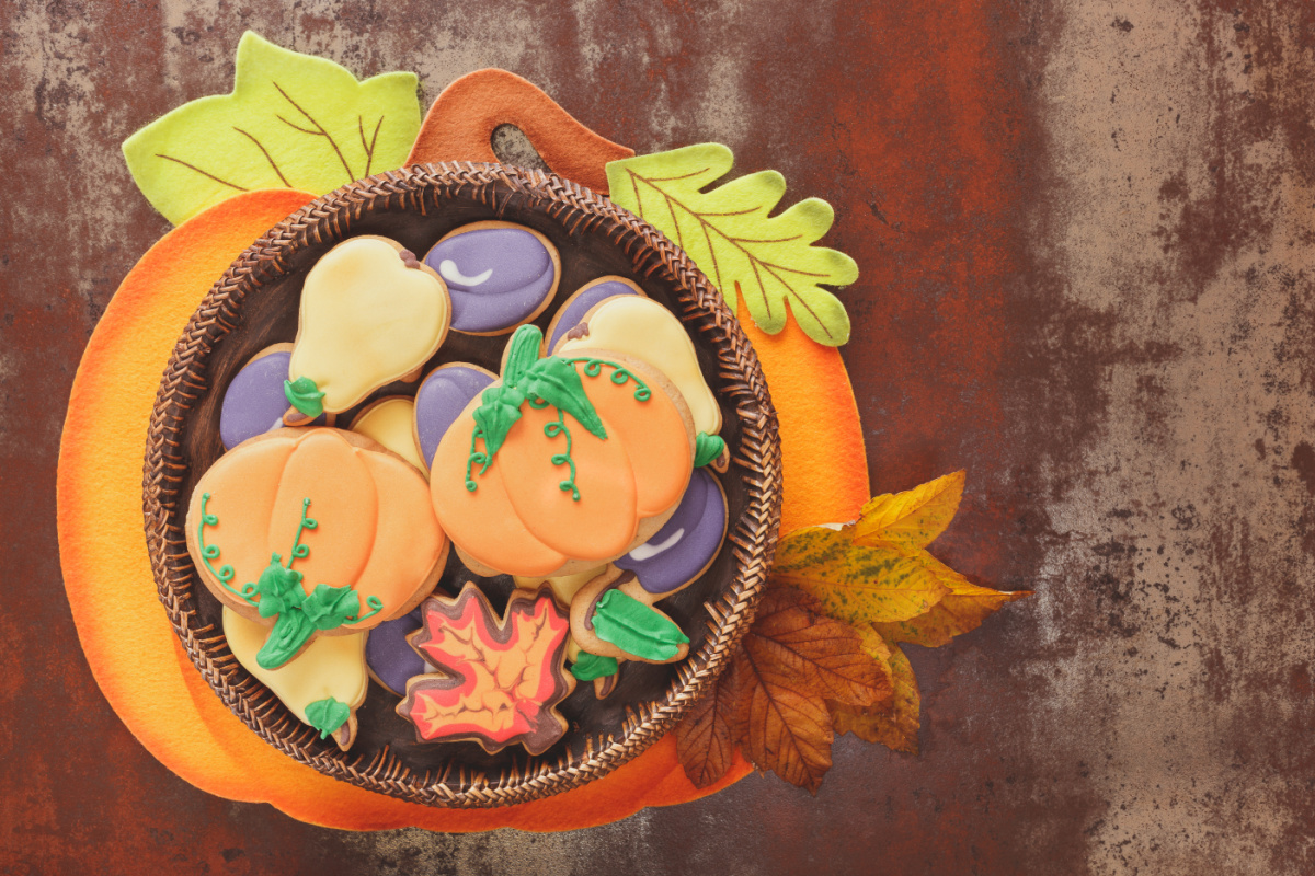 A basket of cookies with pumpkins and leaves in it.