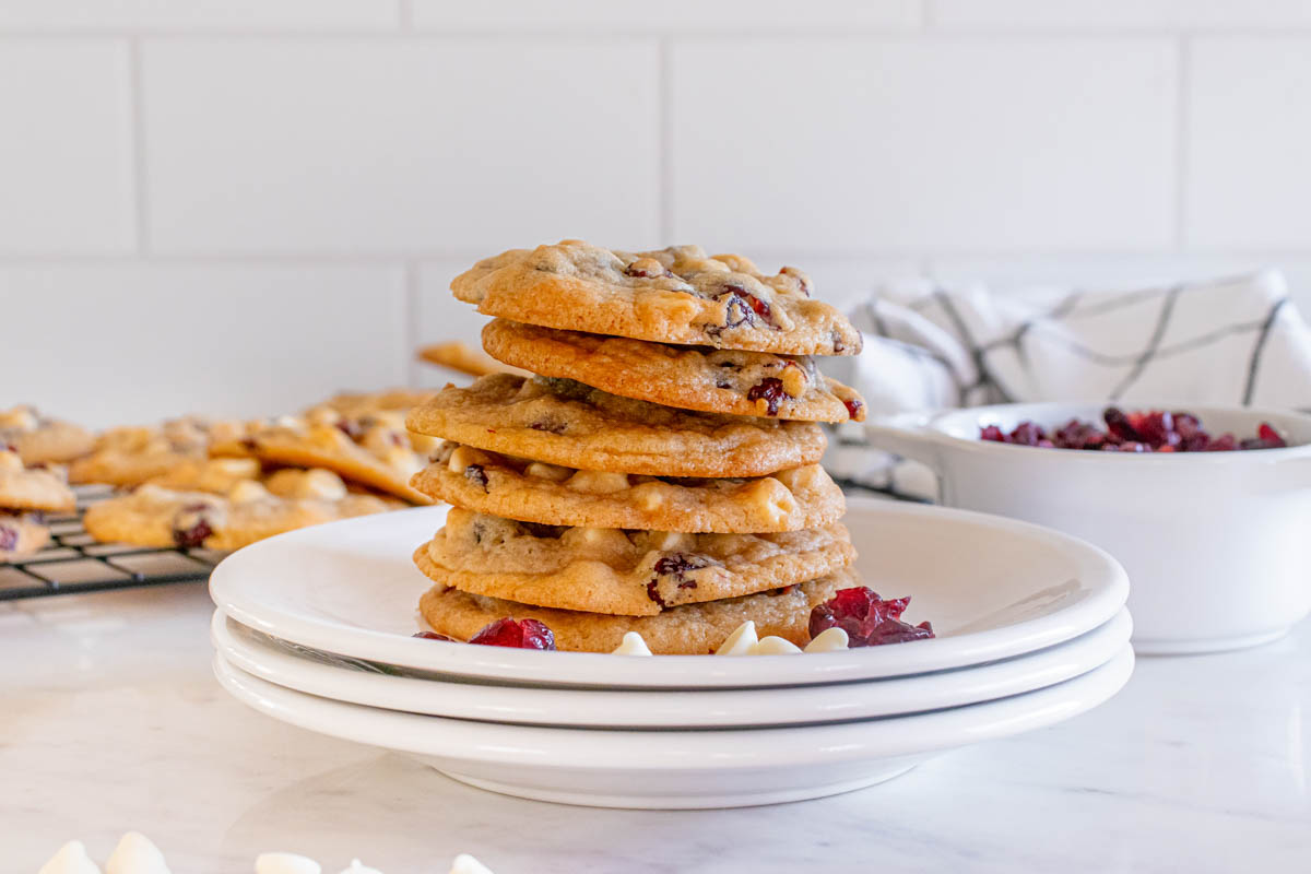 A stack of white chocolate cranberry cookies on a white plate.