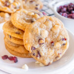 A stack of white chocolate cranberry cookies on a plate.