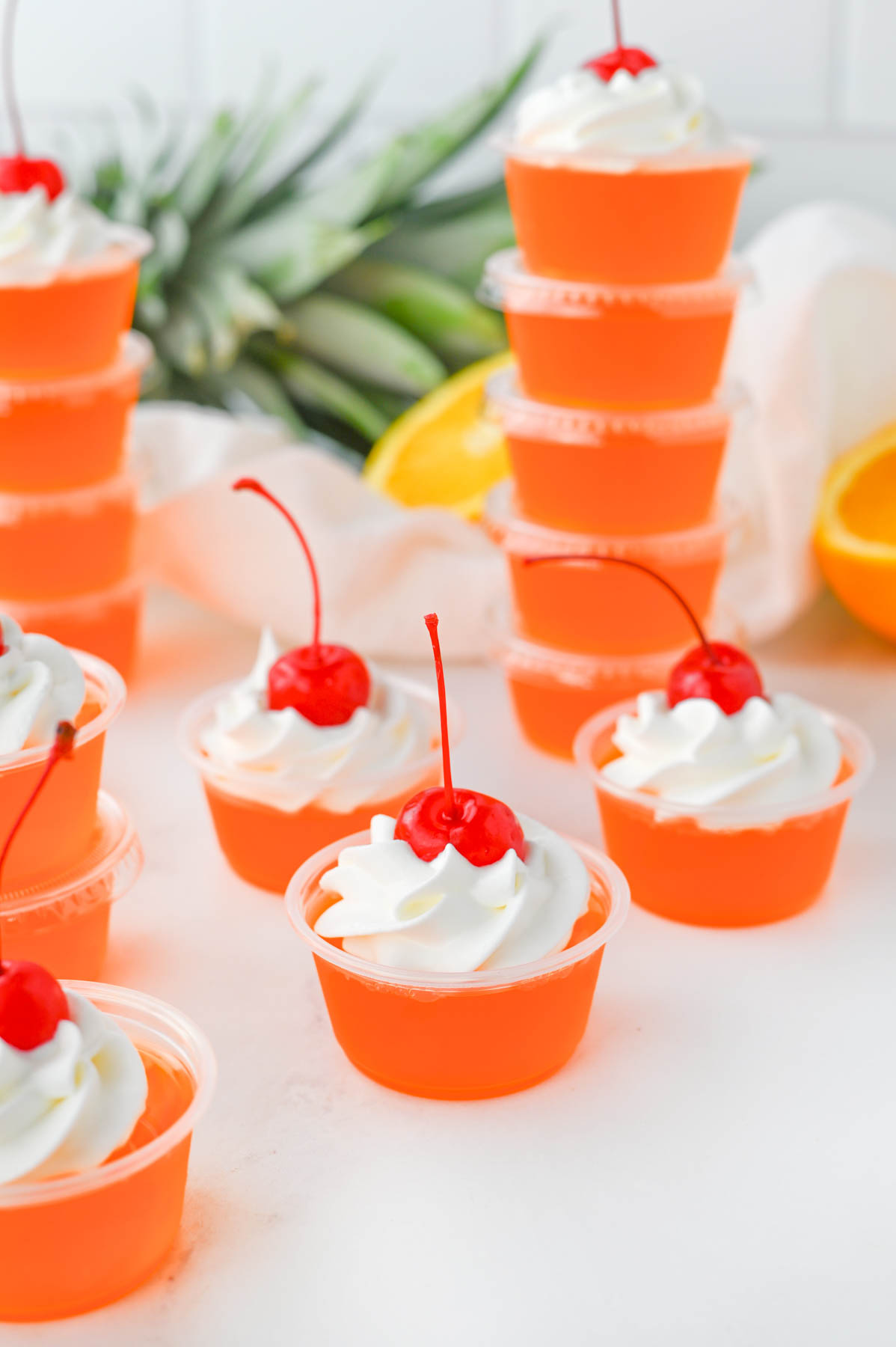 A group of bahama mama jello shot cups with whipped cream and cherries