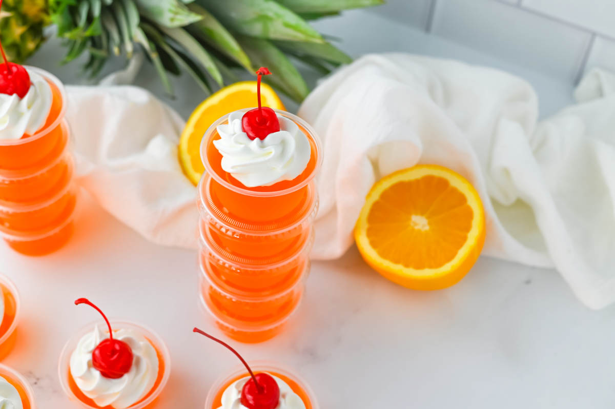 Jello shots topped with whipped cream and orange slices.