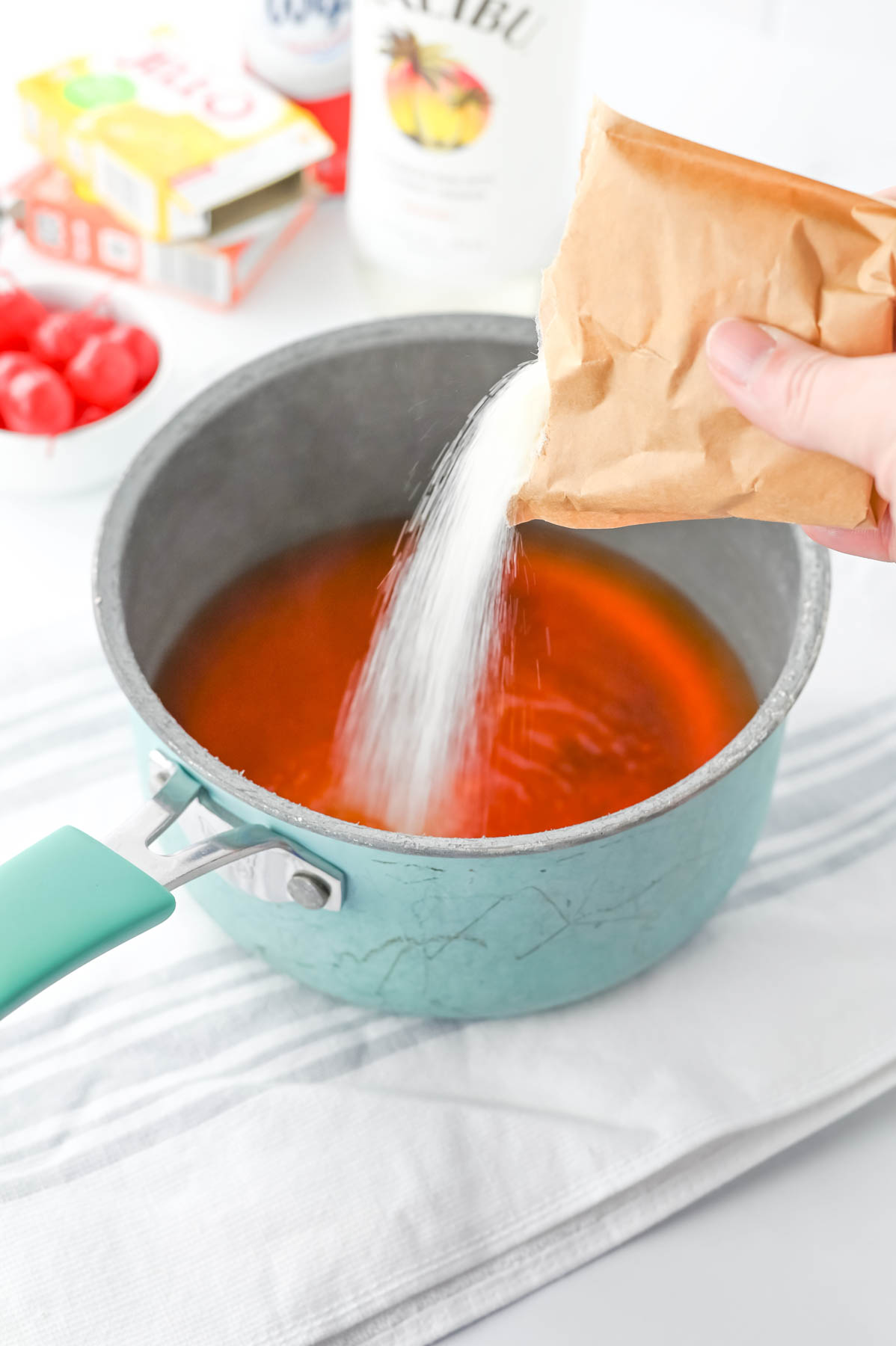 A person is pouring jello powder into a pan.