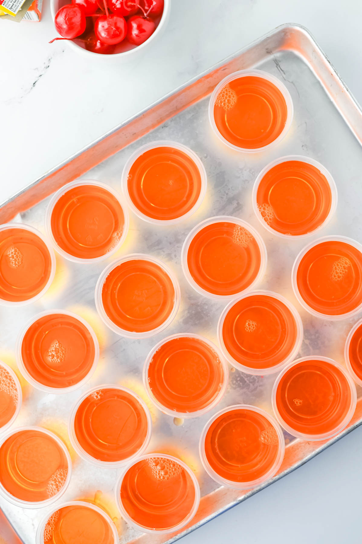 A tray of orange jello cups on a counter.