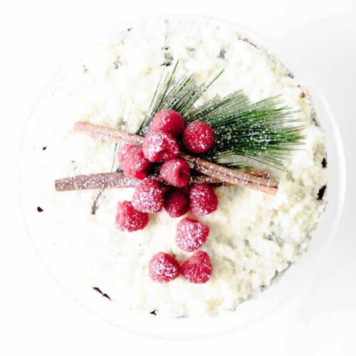 A cake topped with raspberries and pine cones.