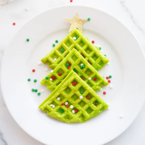 A festive plate with green waffles shaped like a Christmas tree, perfect for creating fun and delicious Christmas breakfast ideas.
