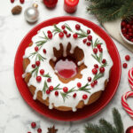A christmas bundt cake with icing and berries on a red plate.