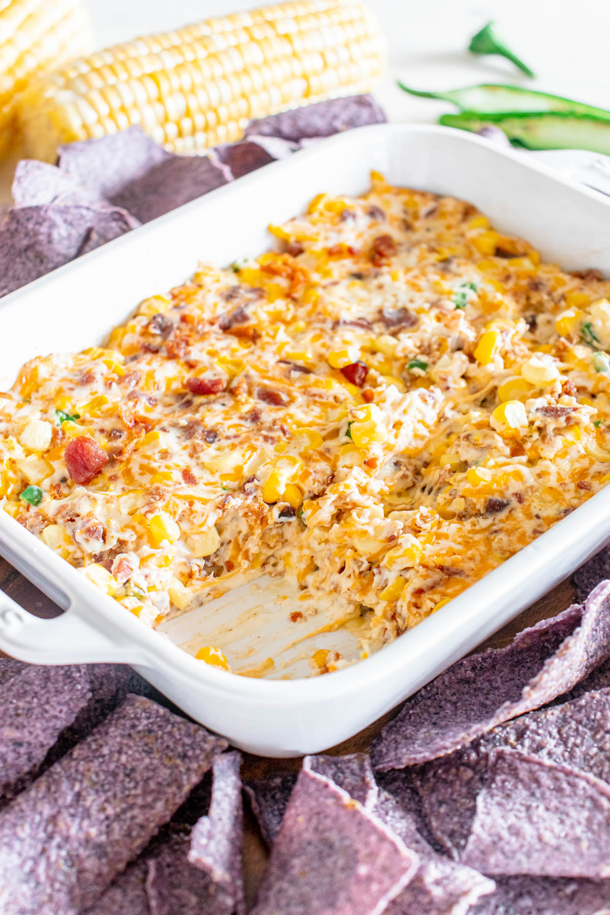 Cheesy corn dip in a white dish surrounded by tortilla chips.
