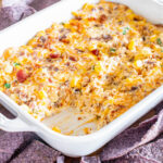 Cheesy corn dip in a white dish with tortilla chips.