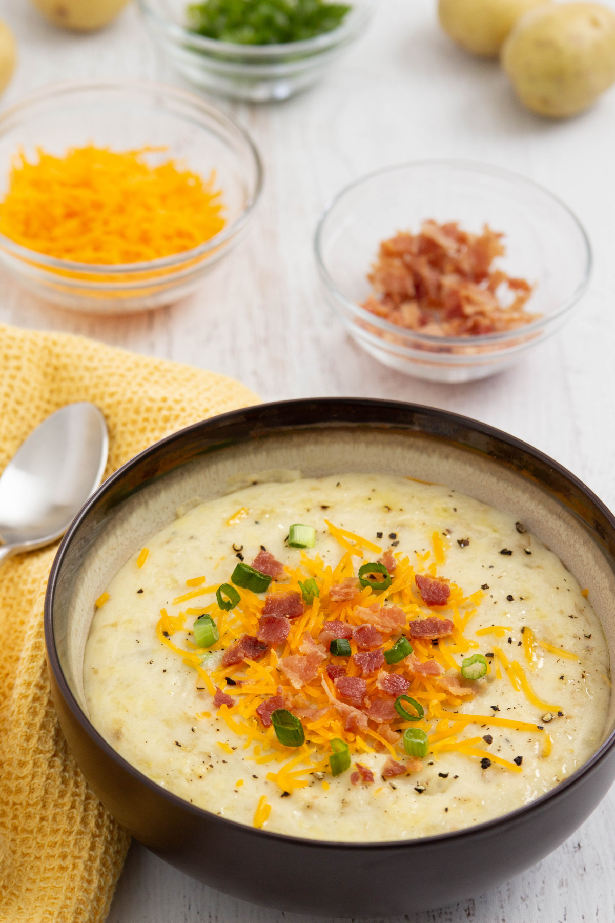 A bowl of cheesy potato soup with bacon and cheese.