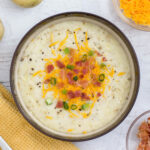 A bowl of cheesy potato soup with bacon and cheese.