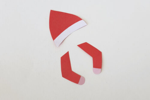 A red elf hat is cut out of paper.